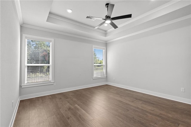 empty room featuring crown molding, ceiling fan, a tray ceiling, and dark hardwood / wood-style flooring