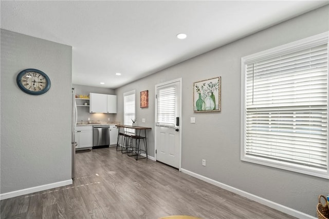 kitchen with stainless steel dishwasher, white cabinets, and hardwood / wood-style flooring