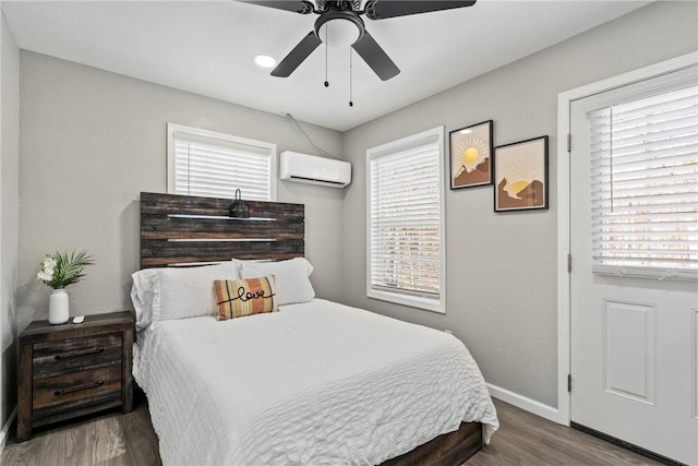 bedroom with ceiling fan, a wall unit AC, and hardwood / wood-style flooring