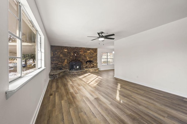 unfurnished living room with ceiling fan, a wood stove, and hardwood / wood-style floors