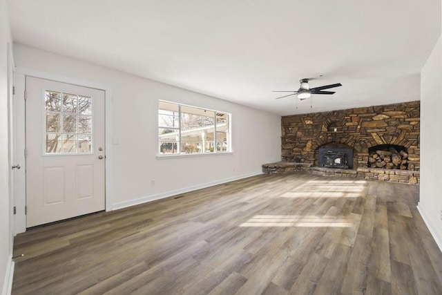 unfurnished living room with ceiling fan, hardwood / wood-style floors, and a wood stove