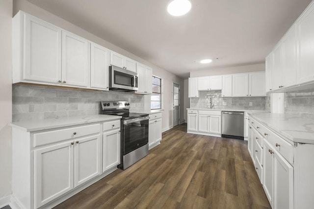 kitchen with dark wood-type flooring, decorative backsplash, white cabinets, appliances with stainless steel finishes, and sink