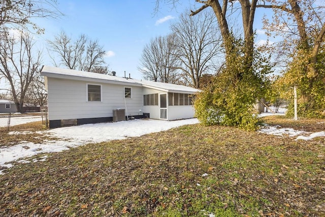 snow covered property featuring central AC and a sunroom