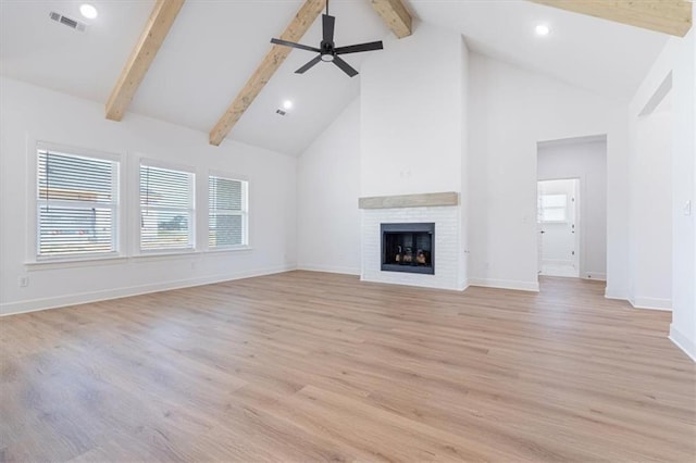 unfurnished living room with light wood-type flooring, high vaulted ceiling, a fireplace, ceiling fan, and beamed ceiling