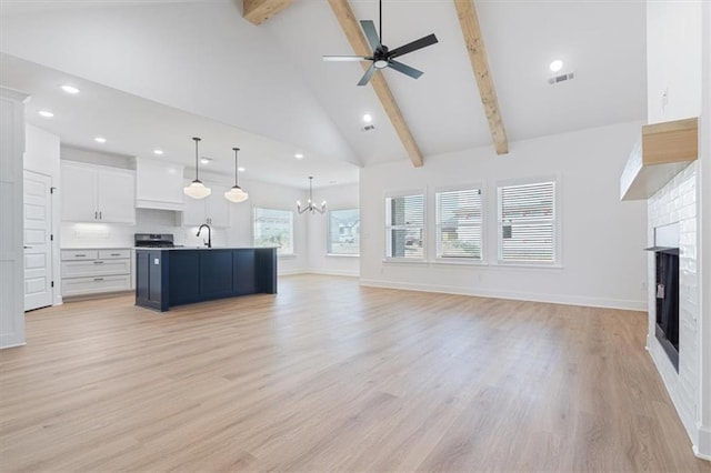 unfurnished living room with ceiling fan with notable chandelier, high vaulted ceiling, light hardwood / wood-style floors, and beamed ceiling