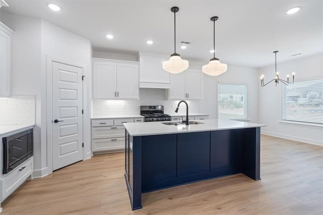 kitchen with white cabinetry, stainless steel stove, built in microwave, and light hardwood / wood-style flooring