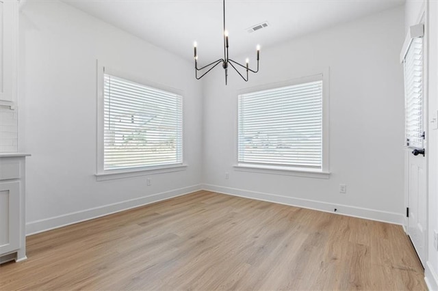 unfurnished dining area with light hardwood / wood-style flooring and a chandelier