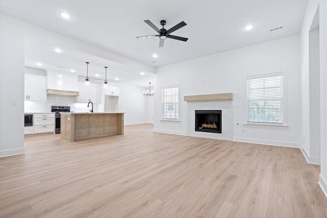 unfurnished living room with light wood-type flooring, ceiling fan, and sink