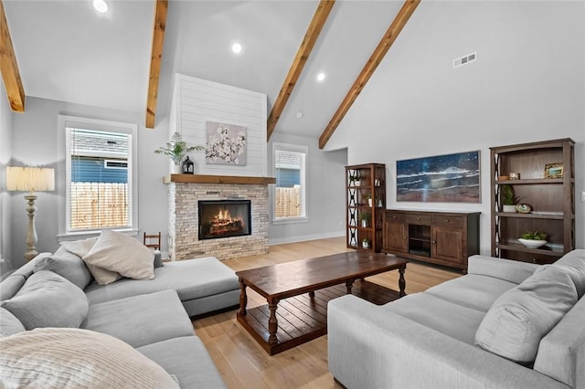 living room featuring high vaulted ceiling, a fireplace, light wood-type flooring, and beamed ceiling