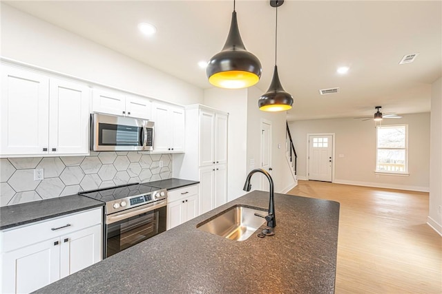 kitchen with tasteful backsplash, visible vents, white cabinets, stainless steel appliances, and a sink