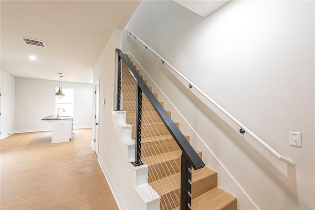 stairway with visible vents, baseboards, and wood finished floors