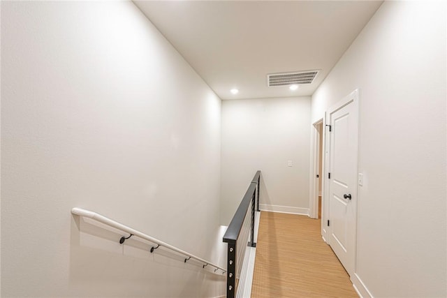 hall featuring an upstairs landing, visible vents, light wood-style flooring, and baseboards