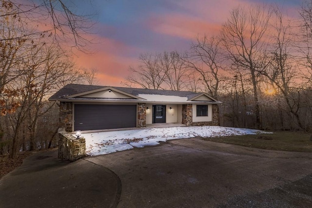 view of front facade featuring a garage, stone siding, and driveway