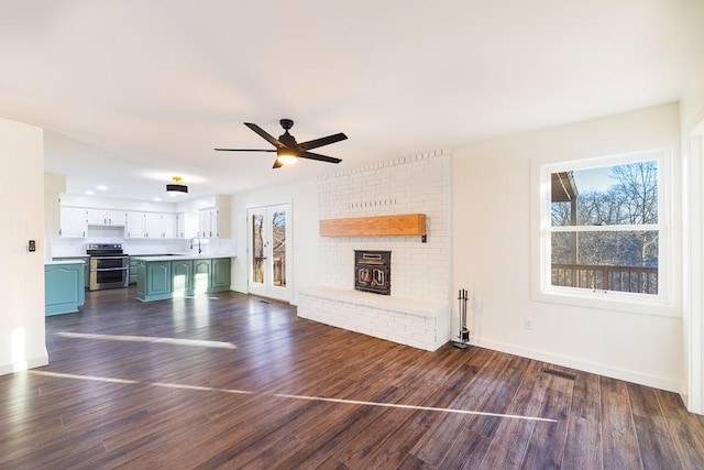 unfurnished living room with dark wood-style floors, ceiling fan, a sink, and baseboards