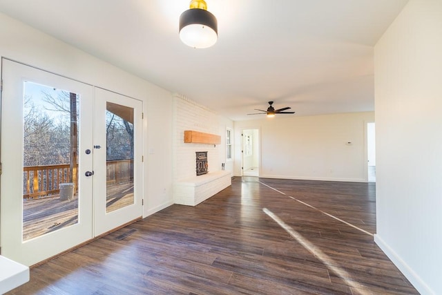 interior space with french doors, a brick fireplace, dark wood finished floors, and baseboards