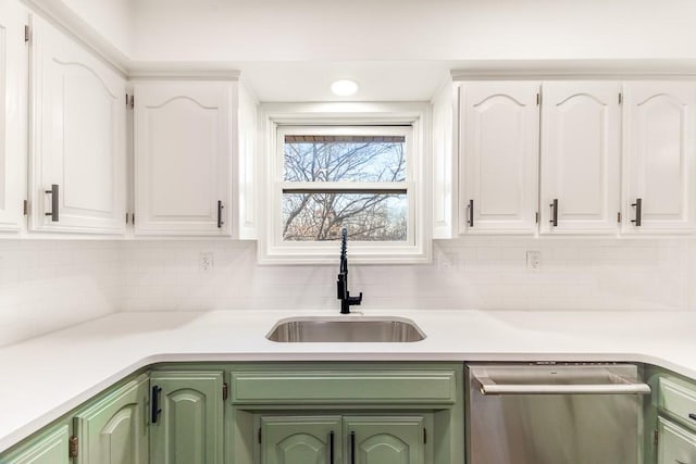 kitchen featuring dishwasher, green cabinets, a sink, and white cabinets