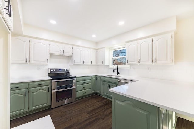 kitchen featuring dark wood-style floors, appliances with stainless steel finishes, a peninsula, a sink, and green cabinetry