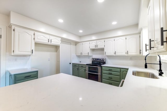 kitchen with range with two ovens, white cabinetry, a sink, and tasteful backsplash