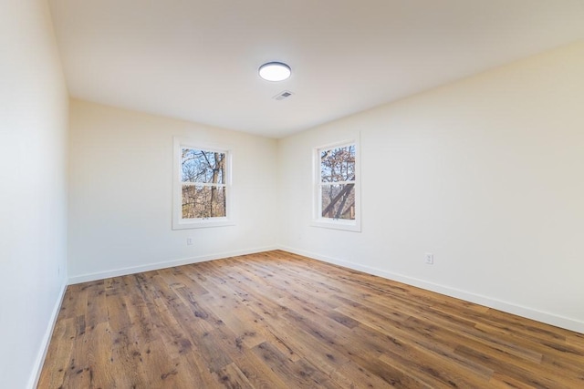 empty room featuring visible vents, baseboards, and wood finished floors