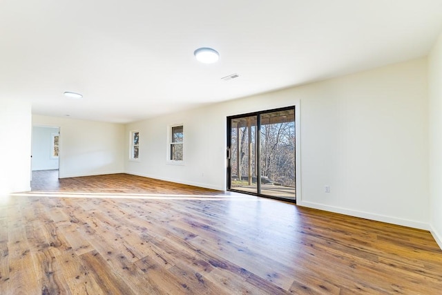 unfurnished room with wood finished floors, visible vents, and baseboards