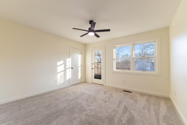 spare room with carpet, visible vents, ceiling fan, and baseboards