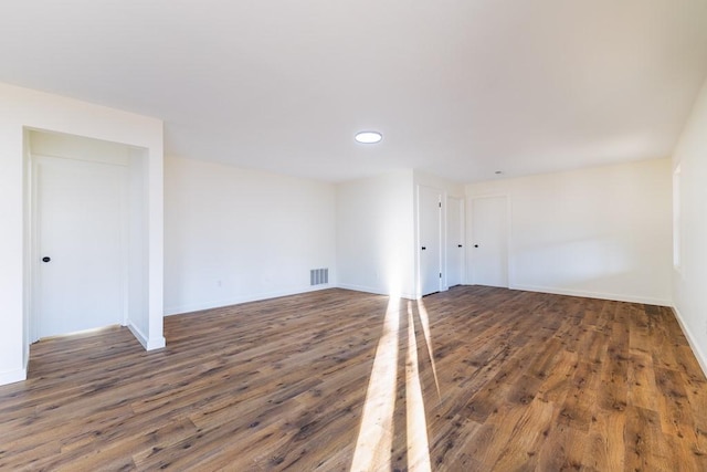 spare room with wood finished floors, visible vents, and baseboards