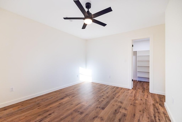 empty room featuring ceiling fan, baseboards, and wood finished floors