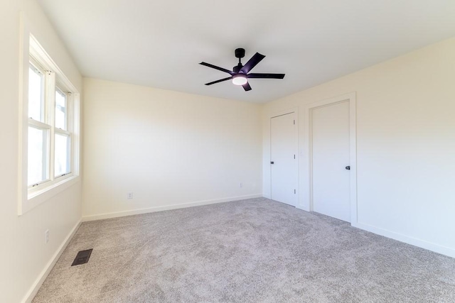 unfurnished bedroom with carpet, visible vents, ceiling fan, and baseboards