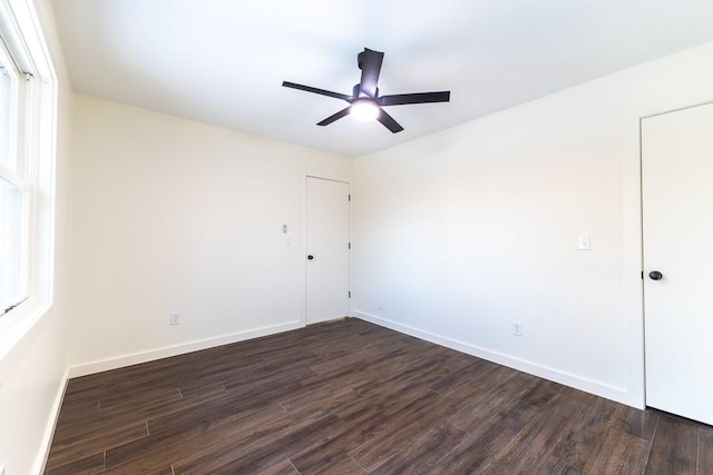 empty room featuring a ceiling fan, dark wood finished floors, and baseboards