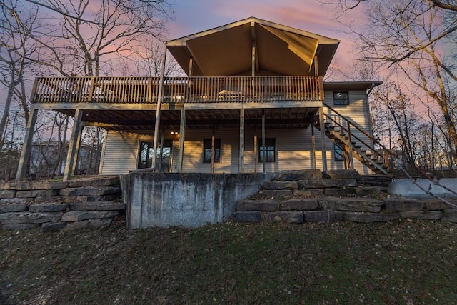 back of property at dusk featuring stairway and a wooden deck