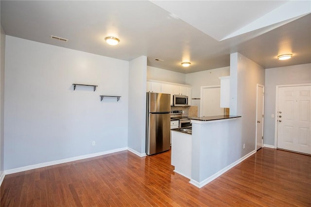 kitchen featuring stainless steel appliances, white cabinetry, tasteful backsplash, and hardwood / wood-style flooring