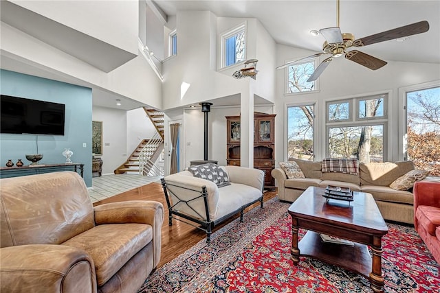 living room with ceiling fan, a towering ceiling, and hardwood / wood-style flooring