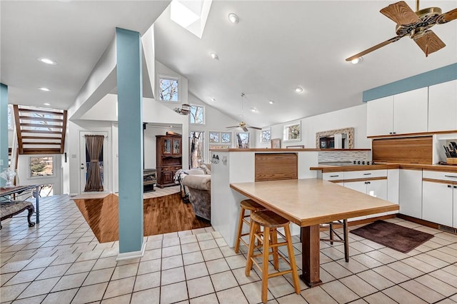 kitchen with ceiling fan, white cabinets, light tile patterned floors, and high vaulted ceiling