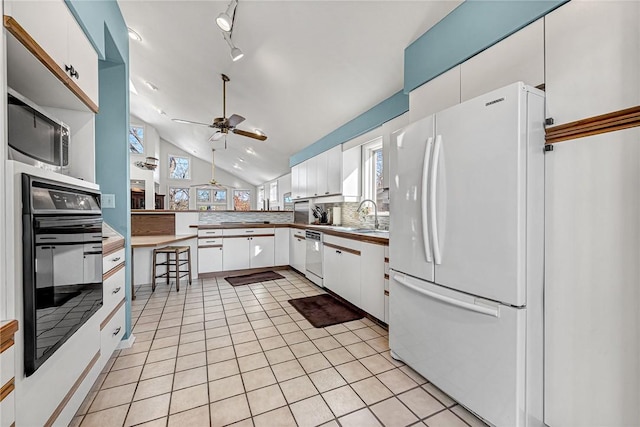 kitchen with lofted ceiling, ceiling fan, tasteful backsplash, white appliances, and white cabinetry