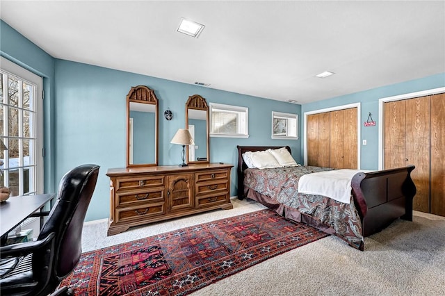 bedroom featuring light colored carpet and two closets