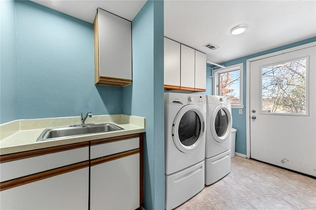 clothes washing area with washer and dryer, sink, and cabinets