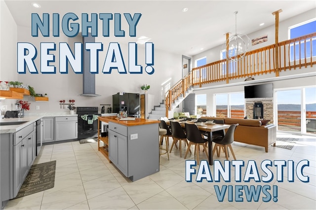 510 Chisholm Trl, Forsyth, MO 65653 - kitchen with black appliances, a towering ceiling, a notable chandelier, butcher block countertops, and gray cabinetry