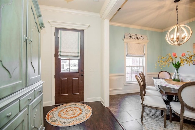 entrance foyer with dark hardwood / wood-style flooring, crown molding, and an inviting chandelier