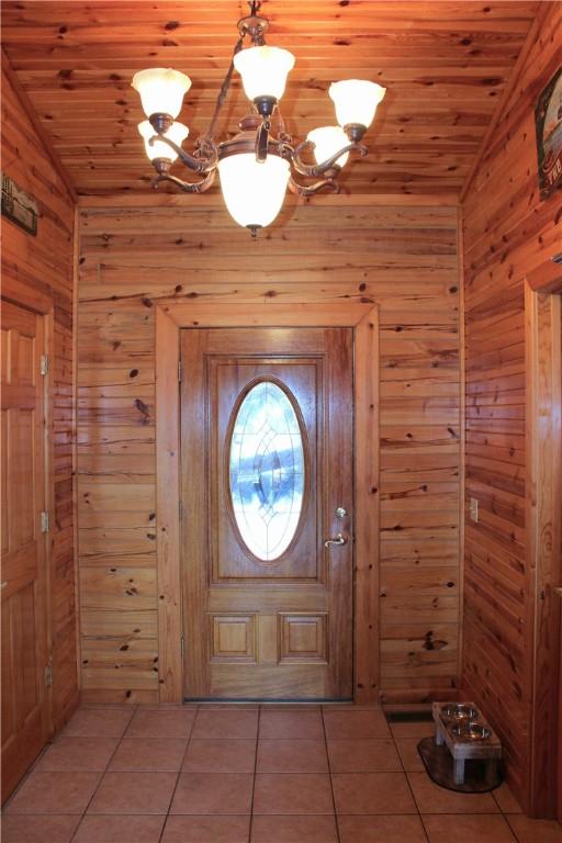 7 Viewpoint Dr, Eureka Springs, AR 72631 - entrance foyer featuring vaulted ceiling, light tile patterned floors, wood walls, a chandelier, and wood ceiling