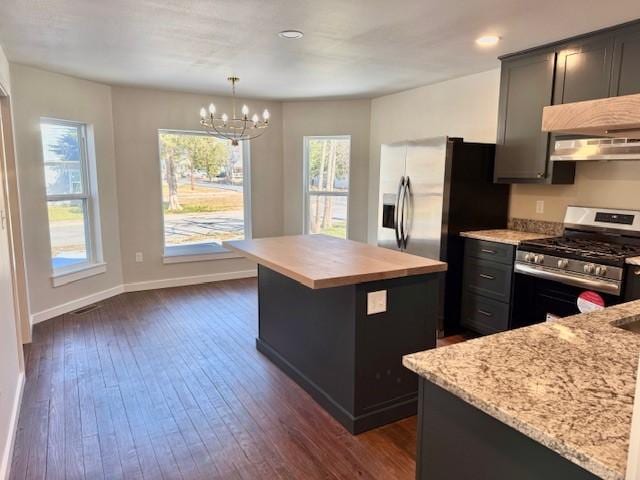 kitchen featuring a notable chandelier, a kitchen island, dark wood finished floors, stainless steel appliances, and baseboards