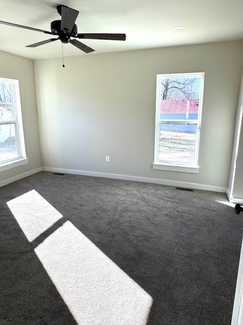 empty room with a ceiling fan, baseboards, and dark colored carpet