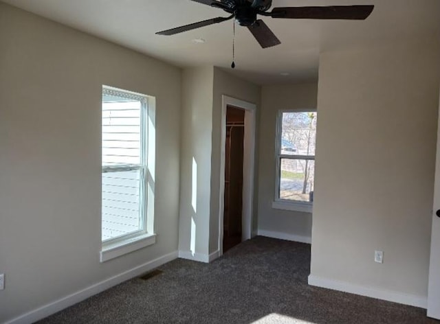 unfurnished bedroom with a closet, dark carpet, a ceiling fan, and baseboards