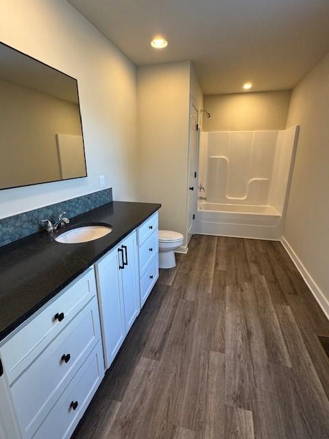 full bathroom featuring vanity, wood finished floors, toilet, and tub / shower combination