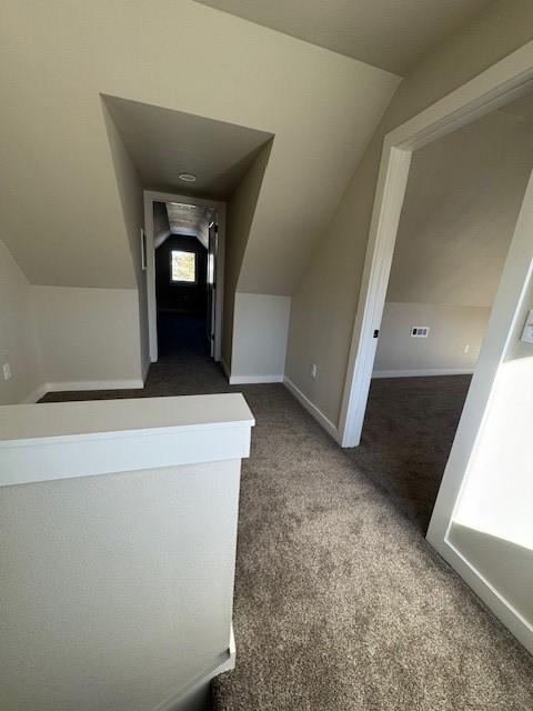 hallway with baseboards, lofted ceiling, and carpet flooring