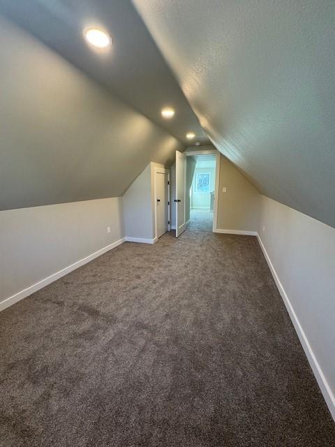 bonus room featuring a textured ceiling, carpet, lofted ceiling, and baseboards