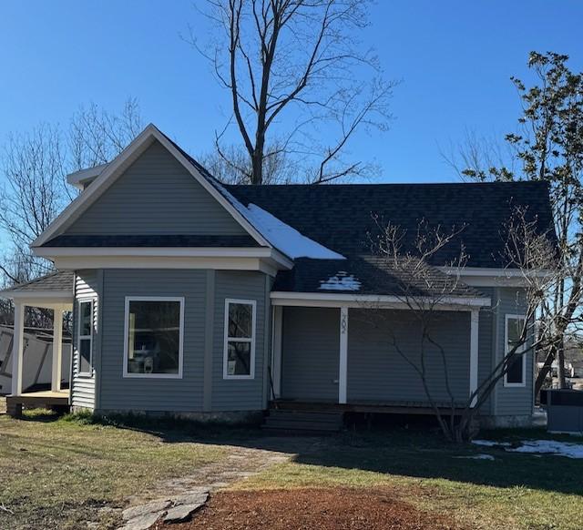 view of front of house with a front lawn, a porch, and a shingled roof