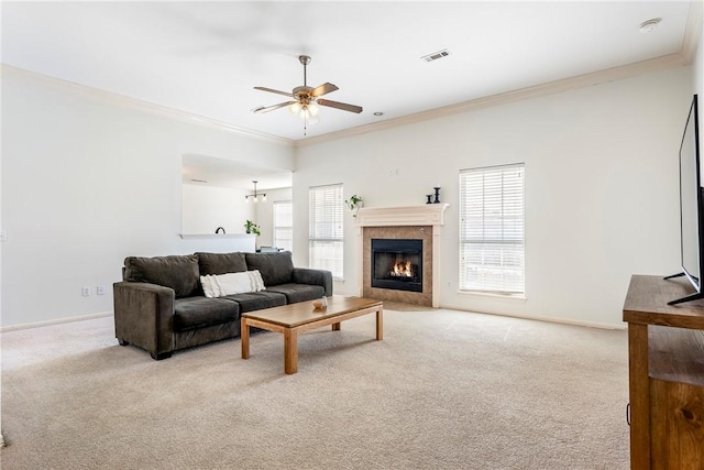 carpeted living room featuring ceiling fan, crown molding, and a fireplace