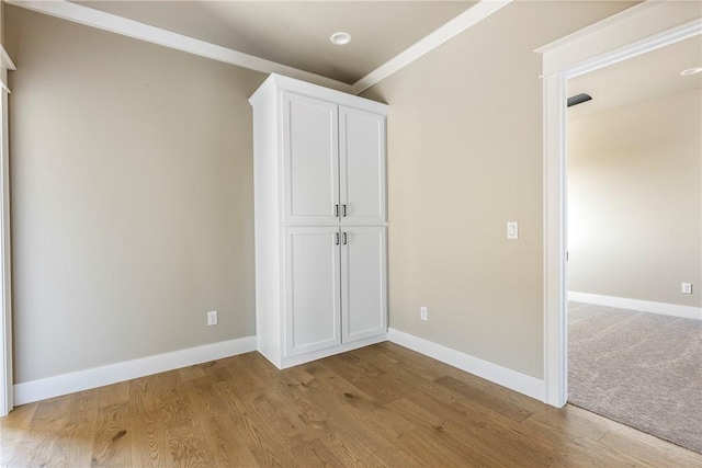 unfurnished bedroom with crown molding and light wood-type flooring