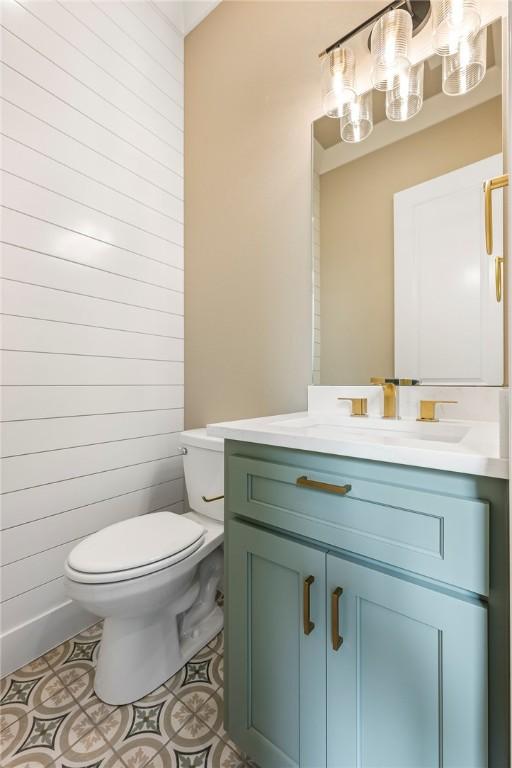 bathroom with toilet, vanity, tile patterned floors, and wooden walls