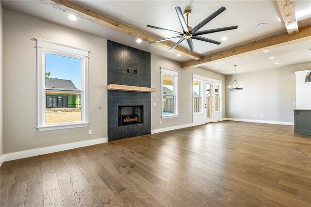 unfurnished living room featuring hardwood / wood-style flooring, a wealth of natural light, ceiling fan, and a fireplace